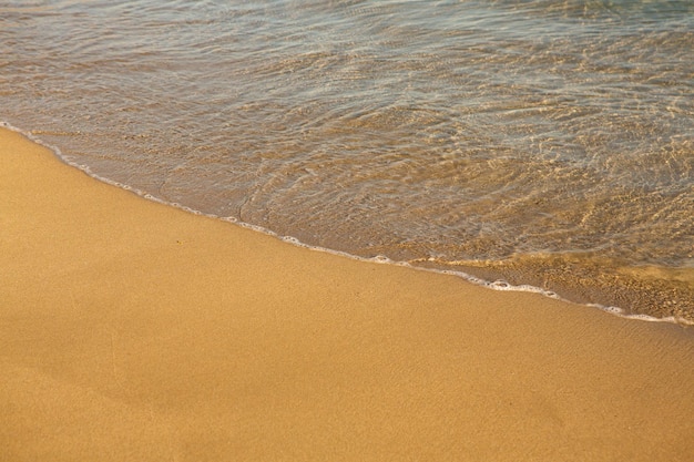 Background with golden sand on the coast of the island of Crete.