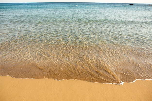 Background with golden sand on the coast of the island of Crete.