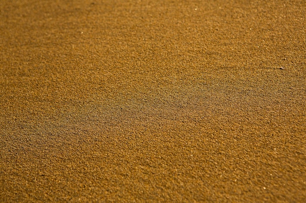 Background with golden sand on the coast of the island of Crete.