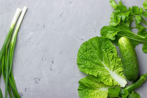 Background with green vegetables, salad, cucumber,green onion and zucchini on gray stone table top