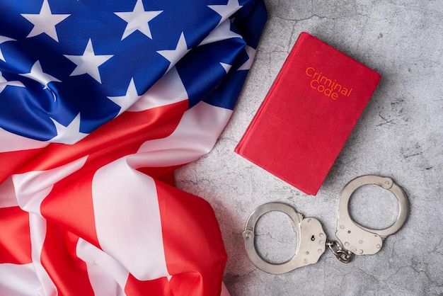 Background with United States flag next to criminal code and handcuffs on a white marble base