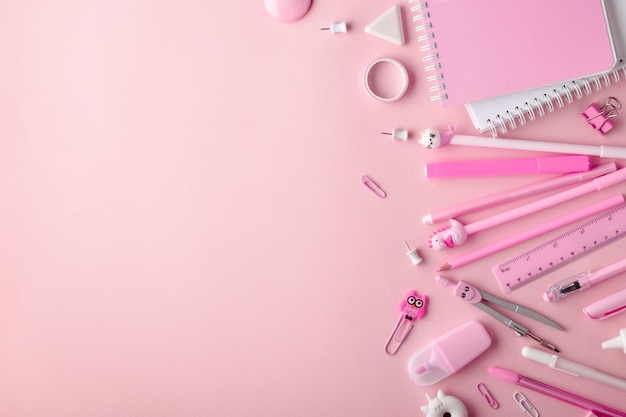 Background with various pink stationery lying on its side on a light pink background Back to school A banner with office elements with space for text Space for copying Flat position top view