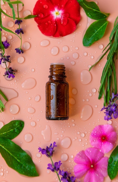 Background with water drops bottle with essential oil and flowers Selective focus