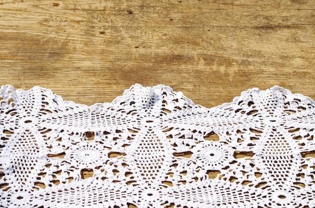 Background of a wooden table and a white crocheted napkin