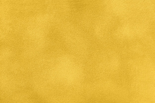 Background of yellow suede matte fabric closeup Velvet matt texture of golden nubuck textile Velveteen pattern Structure of ocher cloth macro