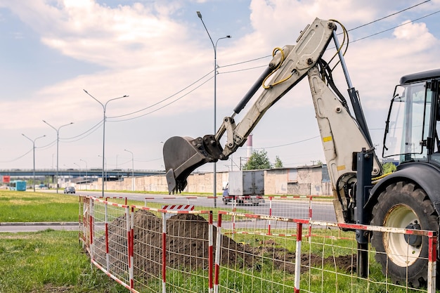 Backhoe loader during excavation work outdoors on a construction site The plot is fenced with temporary mobile fences