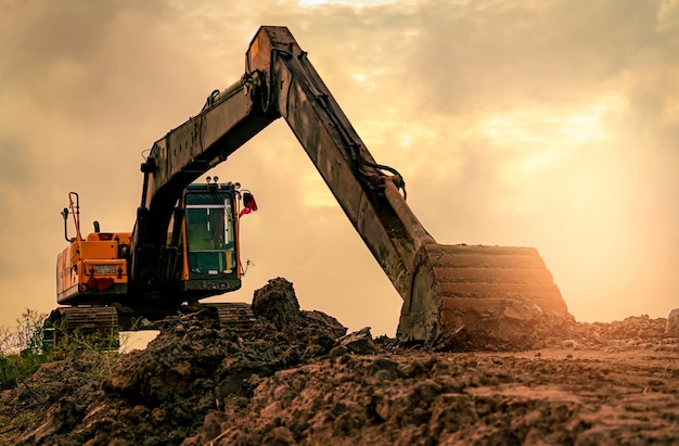 Backhoe parked at construction site after digging soil Bulldozer on sunset sky and clouds backgroud