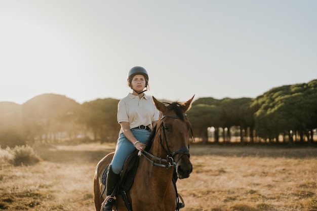 Backlit photo of a young rider riding a horse