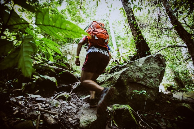 Backpack man running up a rocky mountain slope male trail runner running uphill trekking in Thailand