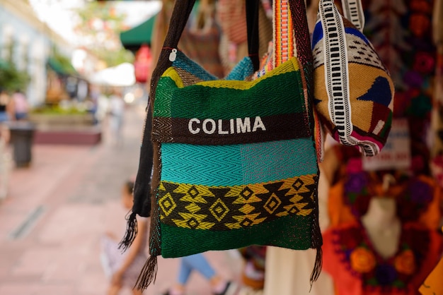 Backpacks purses and handbags made with typical Mexican fabrics hanging outside souvenir stores