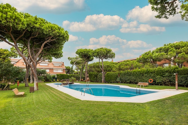 Backyard of residential complex with garden and swimming pool with trees around on sunny day