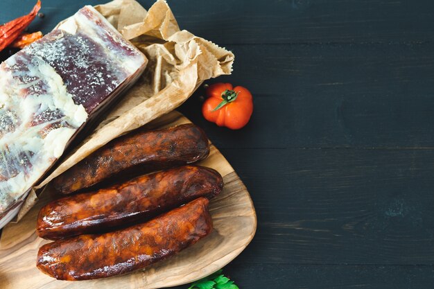 Bacon and cured sausages on a dark background. Copy space.