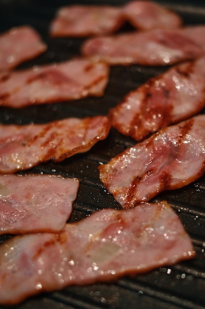 Bacon is being cooked on a grill with the word " bacon " on the bottom.