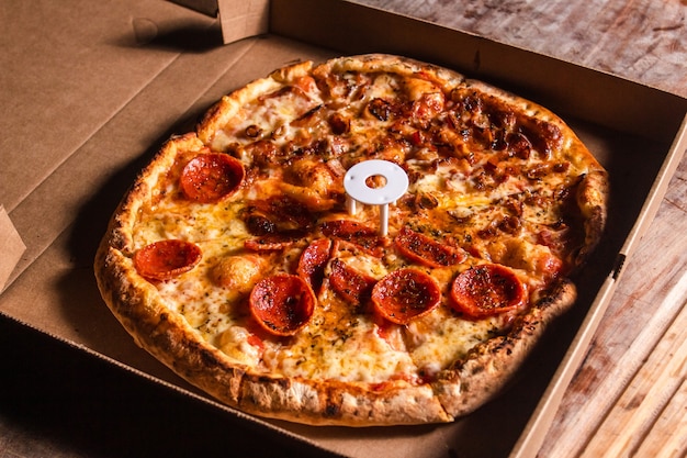 Bacon and pepperoni pizza on top of a cardboard box.