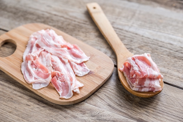 Bacon strips with pepper on wooden spoon