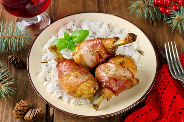 Bacon wrapped chicken legs with rice garnish. Selective focus