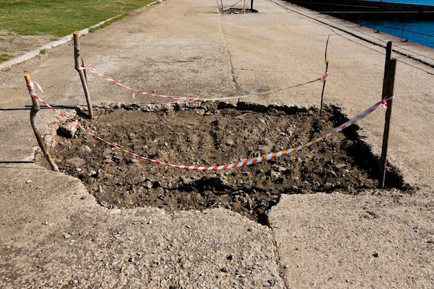 Bad automobile pedestrian road with a large pit and a signal fence