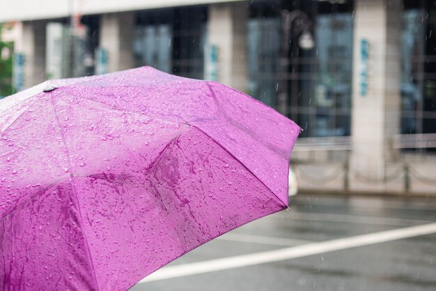 Bad weather. Rainy day. Umbrella with raindrops on the city background. City street style.