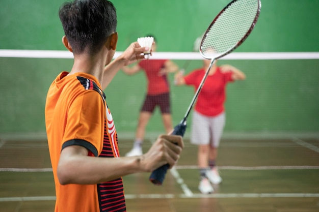 Badminton player in orange uniform ready to serve