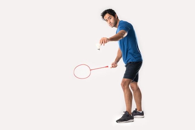 A badminton player in sportswear stands holding a racket and shuttlecock