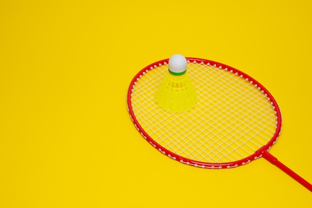 Badminton shuttle and racket isolated on yellow