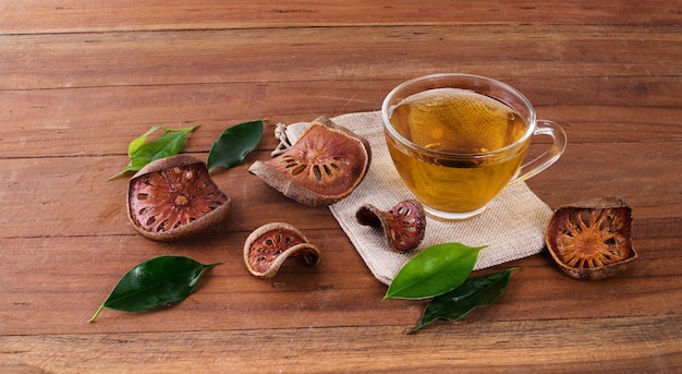 The Bael fruit juice in a glass and dried Bael fruit placed on the wooden