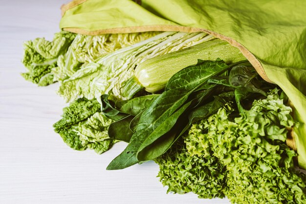 A bag of lettuce is on a white table.