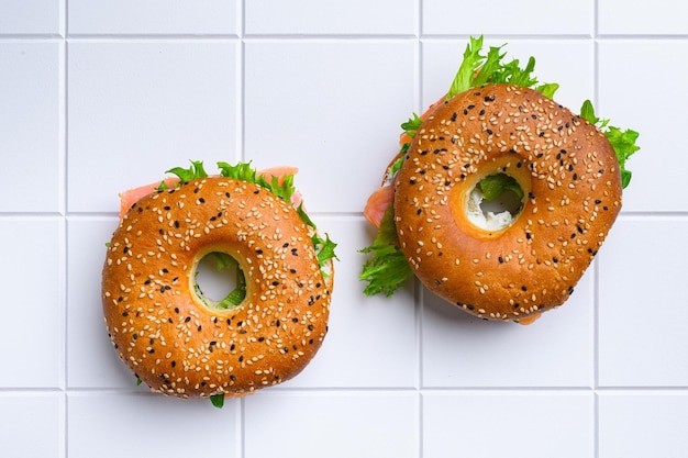 Bagel and lox on white ceramic squared tile table background top view flat lay with copy space for text