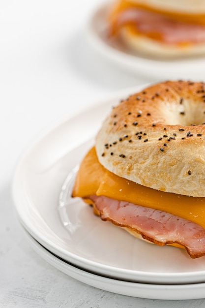 Bagel with ham and cheddar cheese on white plate