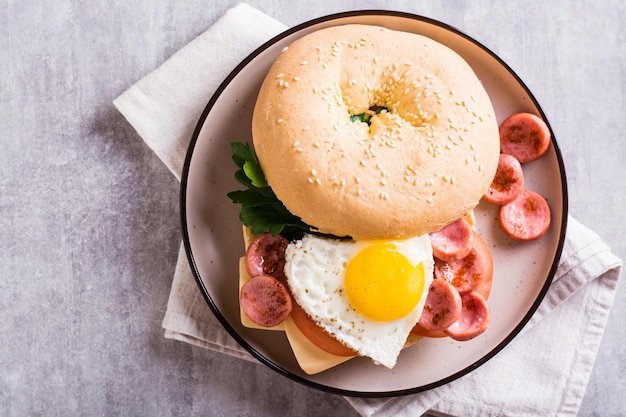 Bagel with heartshaped boiled egg tomato cheese and herbs on a plate Top view Closeup