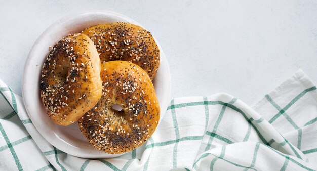 Bagels in a ceramic old bowl with a textile napkin on a light stone or concrete background. Selective focus. Top view. Copy space.