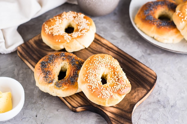 Bagels with poppy seeds and sesame on the board and butter in a bowl Homemade breakfast