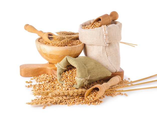 Bags and bowl with wheat grains on white background