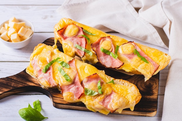 Photo baguette baked with ham cheese and basil on a wooden board