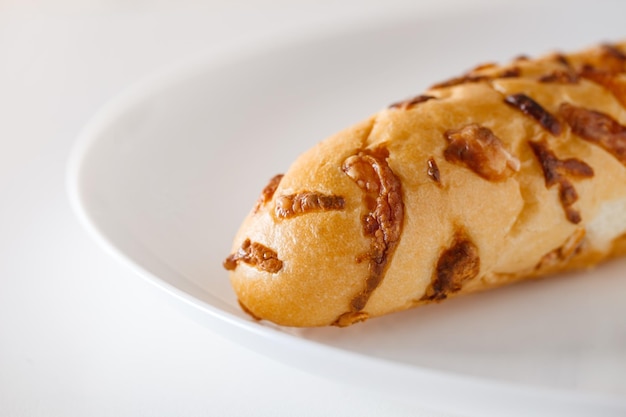 Baguette bun with baked cheese on white plate selective focus