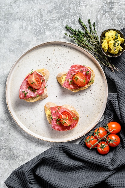 Baguette slices with salami and cherry tomatoes