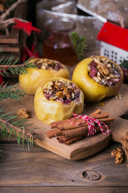 Baked apples stuffed with berries, walnuts and honey on a wooden cutting board.