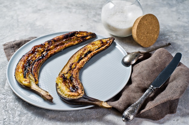 Baked bananas with honey on a grey plate. 