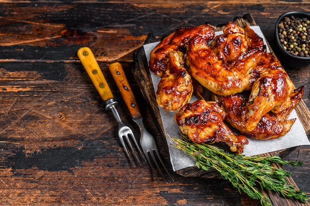 Baked Bbq chicken wings  with dip sauce. Dark wooden background. Top view. Copy space.