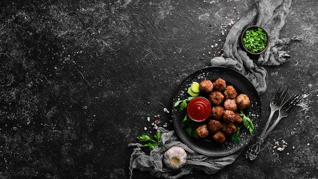 Baked Beef Meatballs with Ketchup on a Black Plate Top view Free space for your text