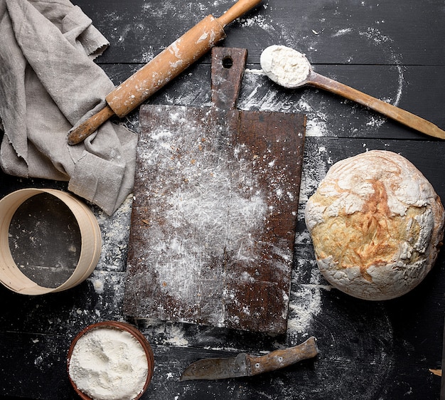 Baked bread, white wheat flour, wooden rolling pin and old cutting board 