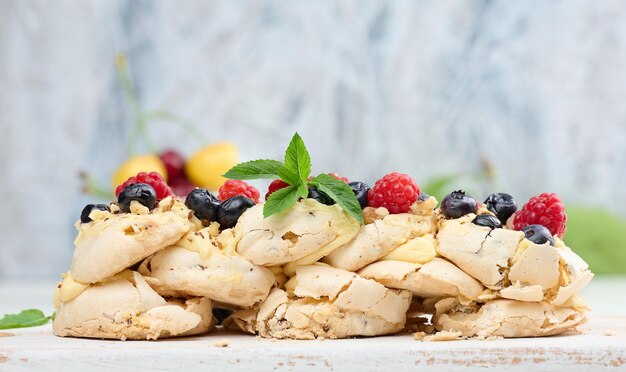 A baked cake made from whipped chicken protein and cream decorated with fresh berries Dessert Pavlova