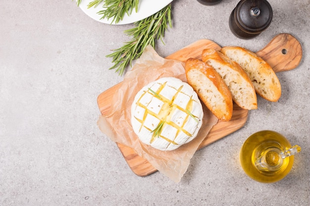 Baked camembert soft cheese. Grilled brie with toasts and rosemary.