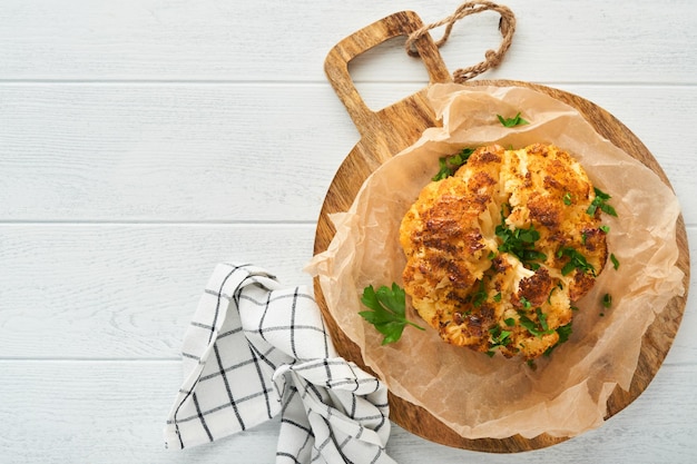 Baked cauliflower Oven or whole baked cauliflower spices and herbs server on wooden rustic board on old white wooden background table Delicious cauliflower Eyal Shani dish Perfect tasty snack