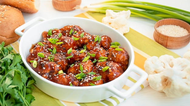 Baked cauliflower in sauce and sesame seeds. Asian cuisine. White wooden background. Copy space.