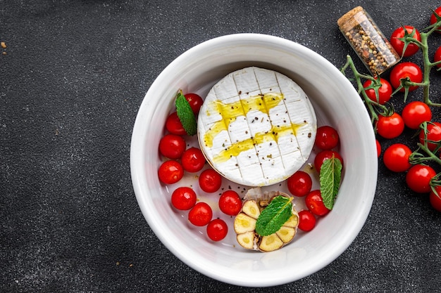 baked cheese Brie or Camembert with tomato, garlic and herbs healthy meal food snack on the table