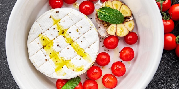 baked cheese Brie or Camembert with tomato, garlic and herbs healthy meal food snack on the table