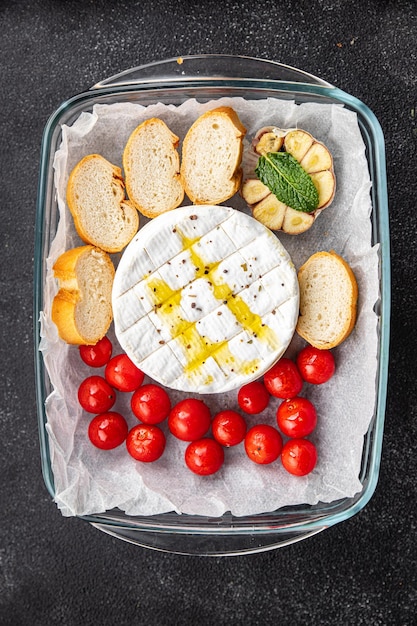 baked cheese Brie or Camembert with tomato, garlic and herbs healthy meal food snack on the table