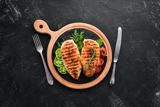 Baked chicken fillet with herbs and spices on a black stone background Top view Free copy space