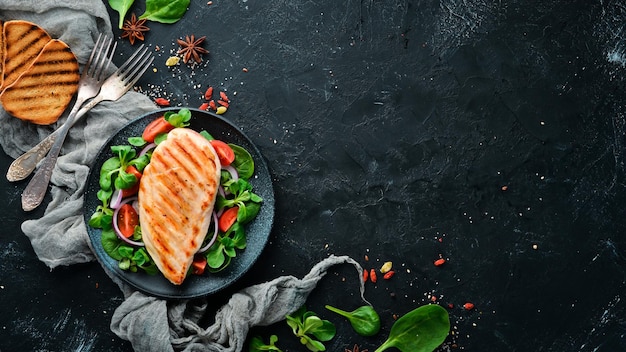 Baked chicken fillet with vegetables In a black plate on a wooden background Top view Free space for your text Flat lay